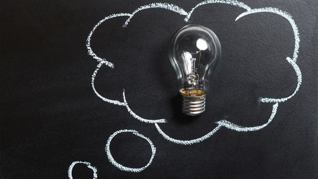 Lightbulb against chalkboard with a thinking cloud around it