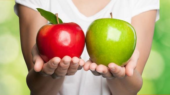 Someone holding a red apple and a green apple side by side
