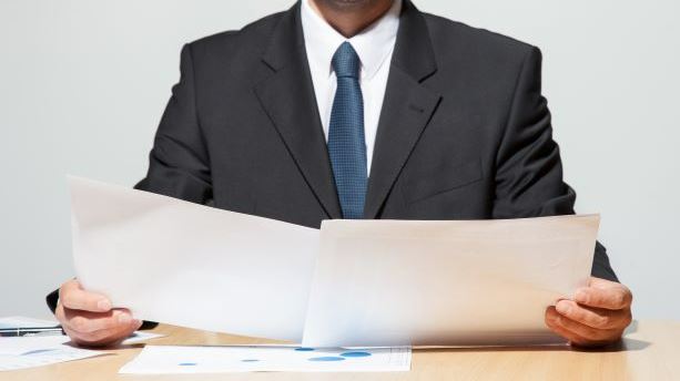 man looking at 2 papers analysing them