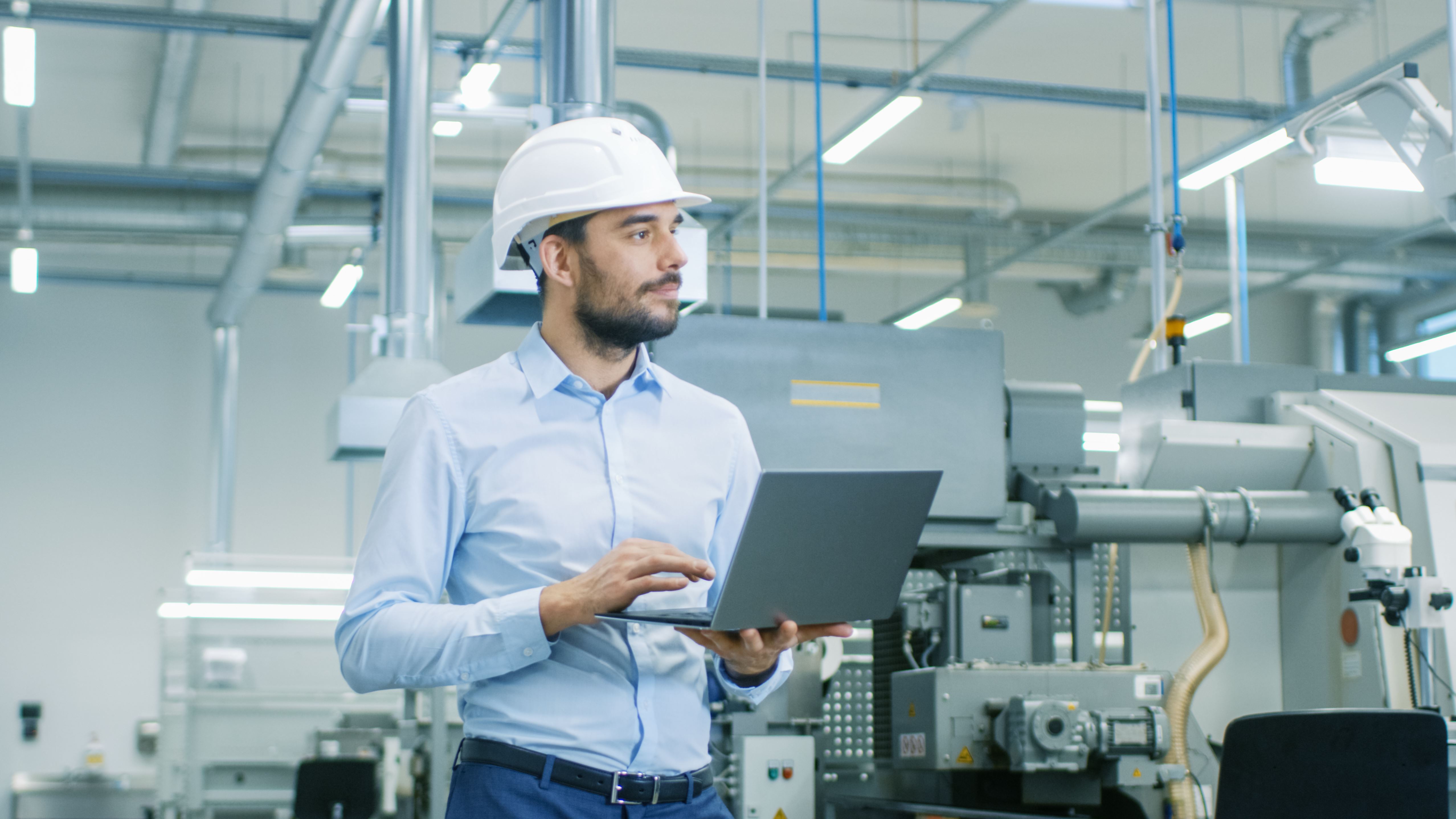 Man holding laptop in a factory