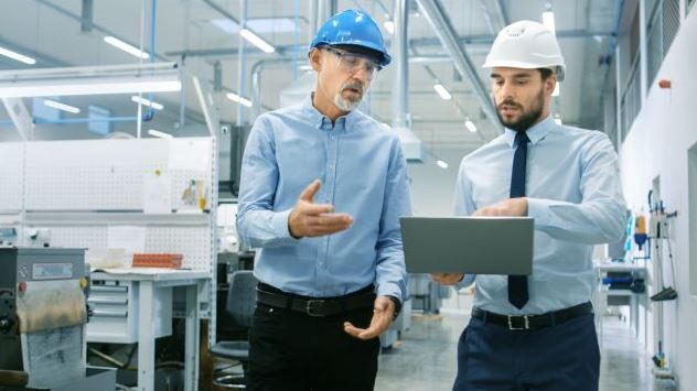 Head of the Department Holds Laptop and Discuss Product Details with Chief Engineer while They Walk Through Modern Factory