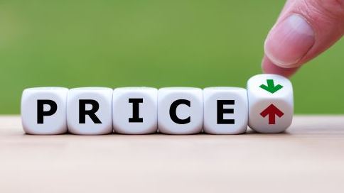 Hand is turning a dice and changes the direction of an arrow symbolizing that the price is going down