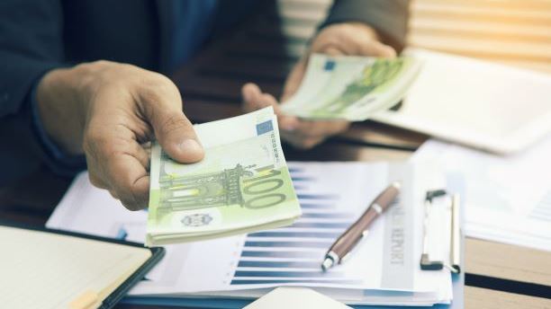 Person in suit handing over stacks of cash over clipboard