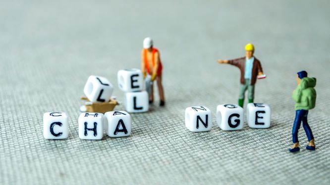 Dice labelled Challenge, three toy workers trying to rearrange
