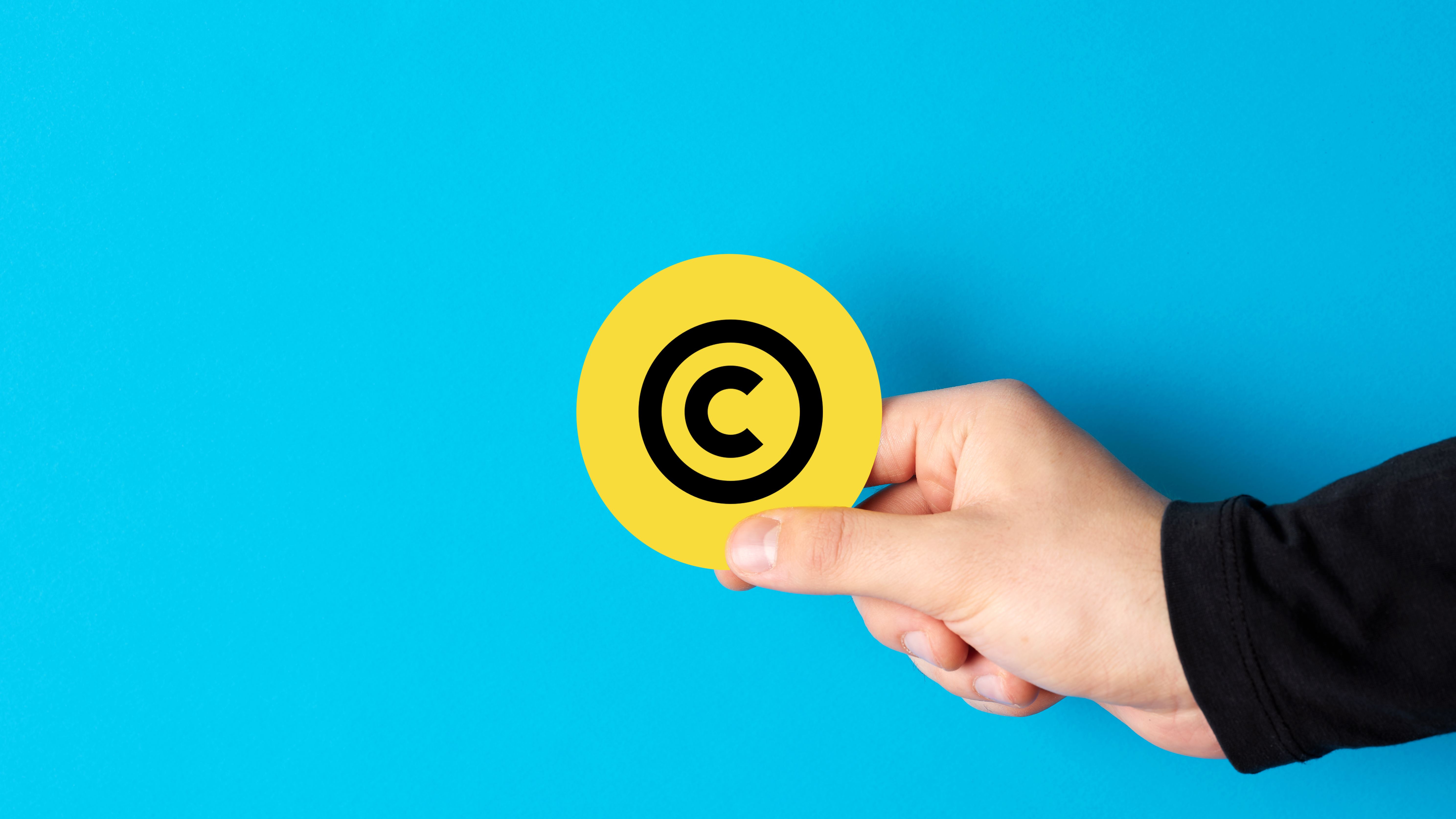 Person holding a copyright symbol against blue background