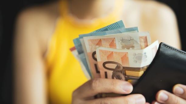 person holding a wallet with euros in