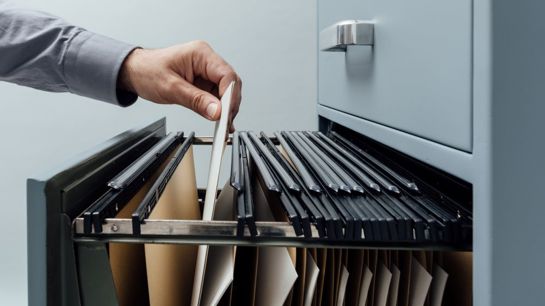 Office Clerk Searching For Files Into A Filing Cabinet Drawer Close Up